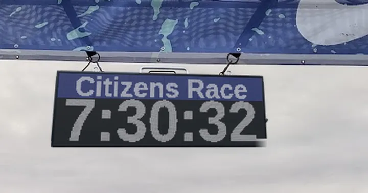 A race clock hanging from a finish truss, showing Citizens Race and 7:30:32